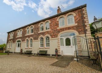 Exterior of The Old Power House converted to a large, 2-storey holiday cottage with two rows of five double windows.