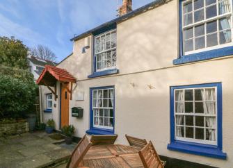 Exterior of asemi-detached restored fisherman's cottage with a paved courtyard in Appledore.