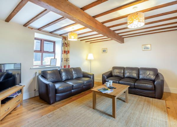 Pine-beamed lounge corner with twin sofas and wide-screen TV.