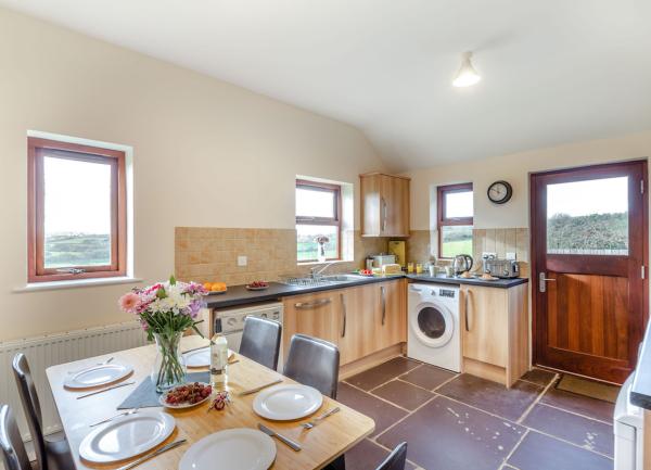 Welsh country cottage kitchen with late tiles, fitted units and dining table.