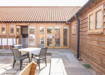 L-shaped exterior of a wooden barn conversion with floor-to-ceiling folding windows.