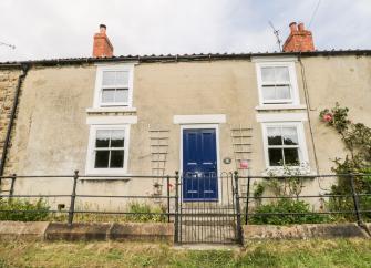 Front exterior of a double-fronted terrace cottage with large sash windows and a front garden