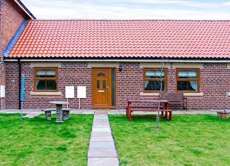 A paved footpath leads to the fron tdoor of a single-storey, brick-built Skinningrove holiday cottage