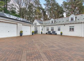 A large inverness-shire holiday cottages and two double garages surround a large block-paved courtyard.