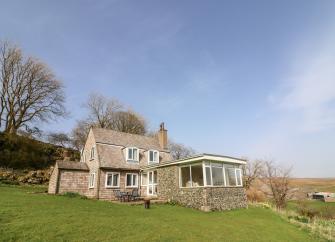 Exterior of an Ingleton holiday cottage overlooking a garden in a rural location.