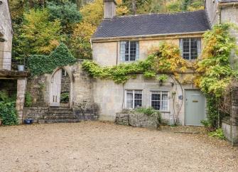 A wisteria clad, semi-detached Cotswold country cottage overlooks a shingled courtyard