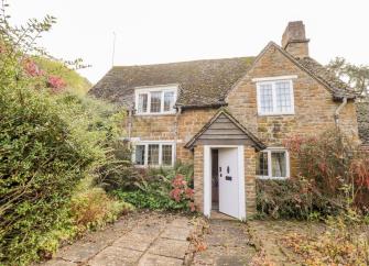 2-storey stone-built Cotswold Cottage surrounded by a mature garden.