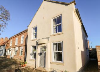 A gabled end-of terrace North Yorkshire holiday cottage overlooking a small front garden.