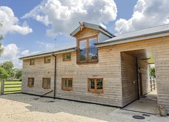 Exterior of a 2-storey wooden barn converted to a New Forest holiday cottage