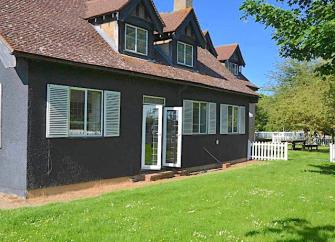Semi-detached holiday cottages on Osea Island with dormer windows in the roof and French windows, overlooking a large lawn
