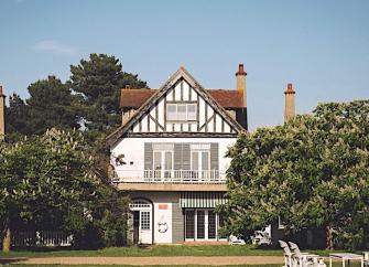 Gable end of a 3-storey period house with 2st floor balcony flanked by mature treees