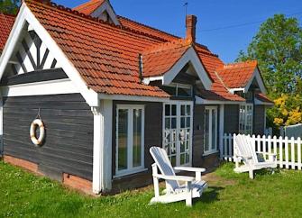 A timber-framed holiday cottage on Osea Island with two sun-loungers on its lawn