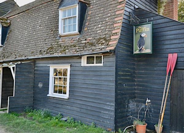 Front of a clapper-boarded pub with a pub sign.