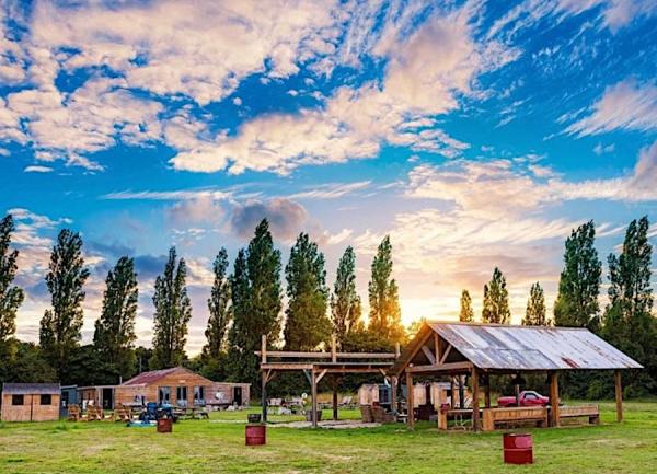 A field with a large open-sided BBQ shelter.