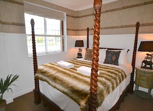Double-bedroom with 4-poster bed and bedside tables with lamps.