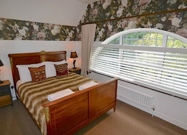 Double beroomn with bed, bedside cabinets, table lamps and semi-circular window..