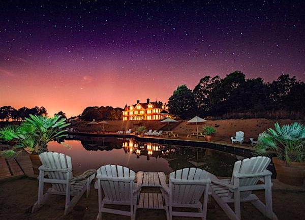 A distant house with illuminated windows glows bright at dusk.