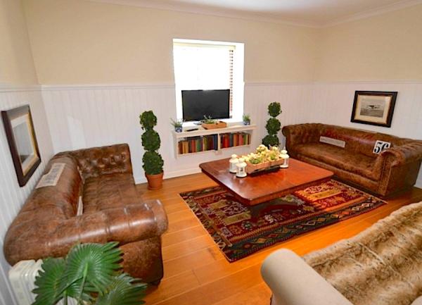 A lounge with luxurious padded leather sofas, coffee table and TV.