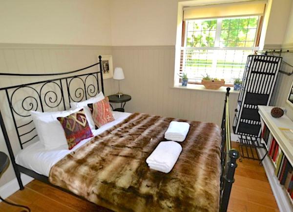 Bedroom with an ornate cast-iron double bed, hanging rail and dressing table