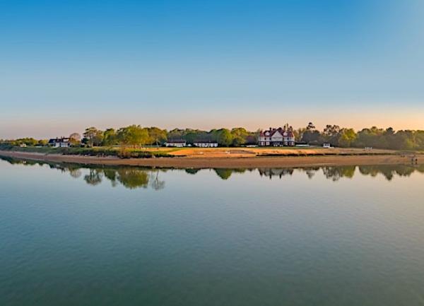 Low-lying Osea Island is mirrored in the water of a calm Thames Estuary.