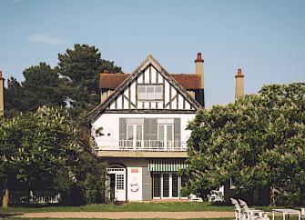 Gable end of an Essex holiday apartment with large balcony and flanked by horse chestnut trees.