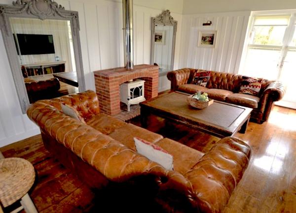 A wood-pannelled lounge with twin leather sofas, coffee table and wood burner.