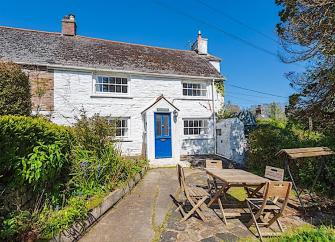 A stone-built Feock holiday cottage overlooks a flagstone patio with outdoor tables and chairs