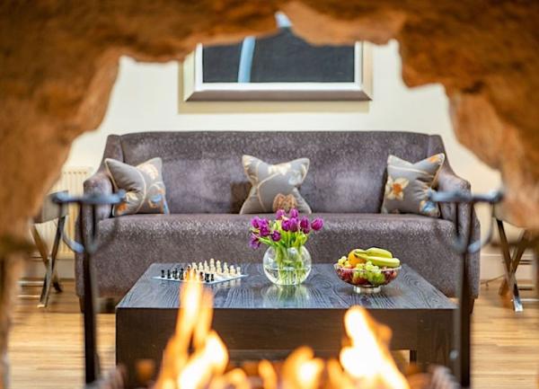 A glimpse of a lounge with a sofa and fruit-laden coffee table through a double-sided fireplace.