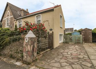 A Torquay holiday cottage overlooks a drive and fllower-filled front garden.