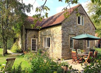 Stone-built Dorset farm cottage with a patio, lawns and mature trees.