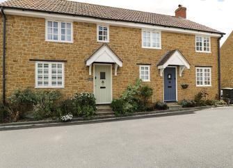 A semi-detached stone-built holiday cottage in Chideock overlooks a quiet village lane.