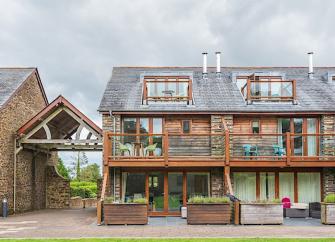3-storey contemporary holiday home with large balcony and patio overlooks a lawn.