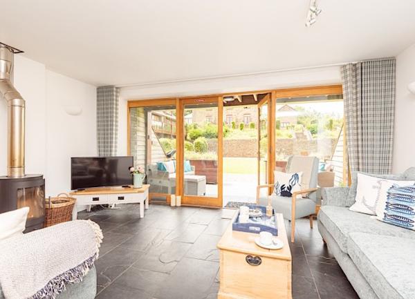 Lounge with sofa, armchairs, TV and coffee table with French windows.