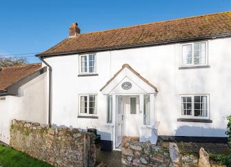 A double-fronted holiday cottage exterior with a small walled front garden