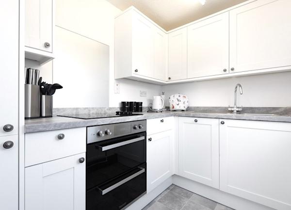 A fitted kitchen with an oven with ceramic hob intedrated with floor and wall-mounted cupboards.