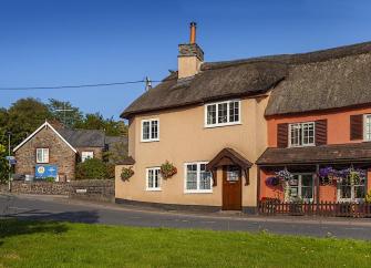 A thatched cottage overlooks a village green.