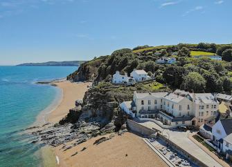 aerial view or a beach with a small seaside village overlooking the sands