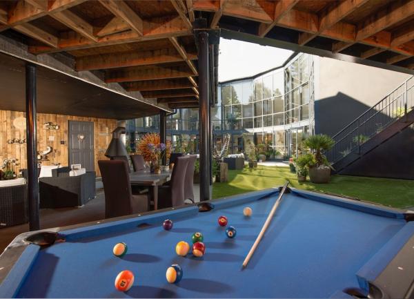 A full-size pool table in a room with bi-fold French windows overlooking a lawned courtyard.