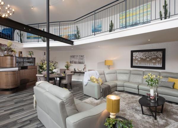A lounge-dining area with an overhead gallery above sofas and the dining table.