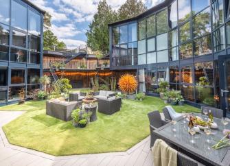 A 3-storey, glass-fronted house curves around a courtyard with a central lawn and sofas