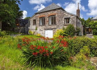 Exterior or a stone-built barn conversion surrounded by a flower-filled garden