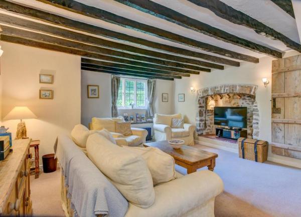 A spacious oak-beamed lounge with a 3piev=ce suit, and a TV in what used to be a fireplace.