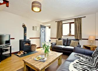 A spacious lounge with sofas, woodburner and coffee table