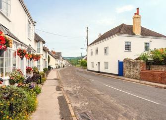 Cottages with hanging flower basket line a quiet village street.