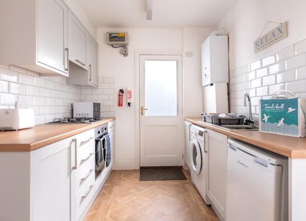 Fitted kitchen with pine worktops, integrated cooker, washing machine and fridge.