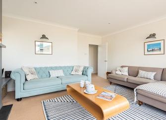 A spacious lounge with 3-sofas and a wooden coffee table.