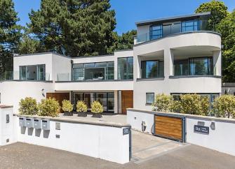 Exterior of a 2 storey contemporary house with wide windows, curved walls and a balcony.