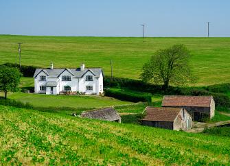 A large farmhouse and barns surrounded by greenfields.