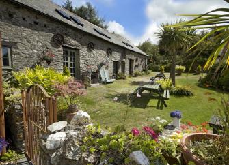 A stone barn conversion overlooks a lawn and flower-filled garden