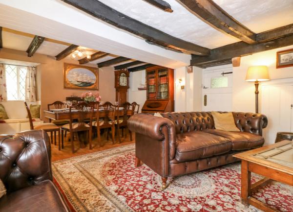 Oak-beamed living area with padded leather sofas and a dining table with 8 chairs.